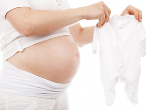 אישה בהריון עם בגד של תינוק